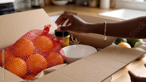 Unboxing fresh oranges and produce from a cardboard delivery box, healthy food delivery.
