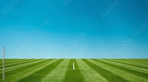 Vast empty grass court under clear bright blue sky with center marking with emphasizing openness tranquility captures meticulously maintained