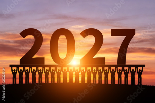 In the morning sun, numerous silhouettes of children are holding up the year 2027