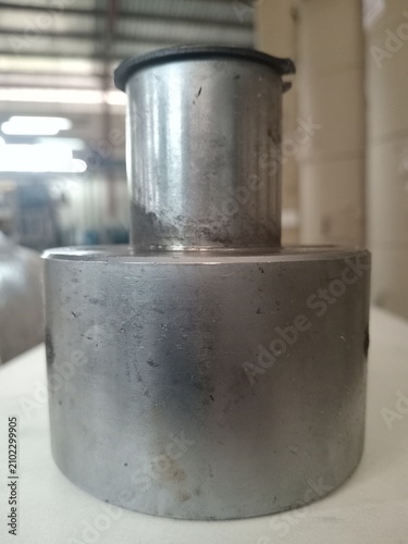 Industrial round metal cylinder shaft component on white table closeup