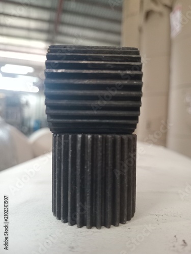 Two industrial steel spur gears stacked on white table in factory workshop background