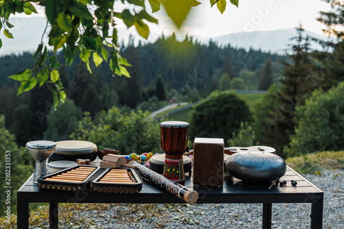 Tableau sur toile Assortment of ethnic musical instruments on a table with a scenic mountain background