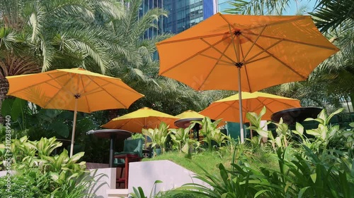 Empty Outdoor Cafe with Orange Umbrellas in Tropical Garden of city Hotel