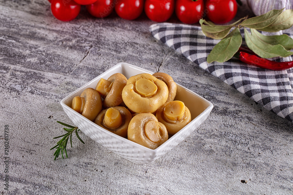 Fototapeta premium Marinated champignon mushrooms in white bowl with herbs and cherry tomatoes
