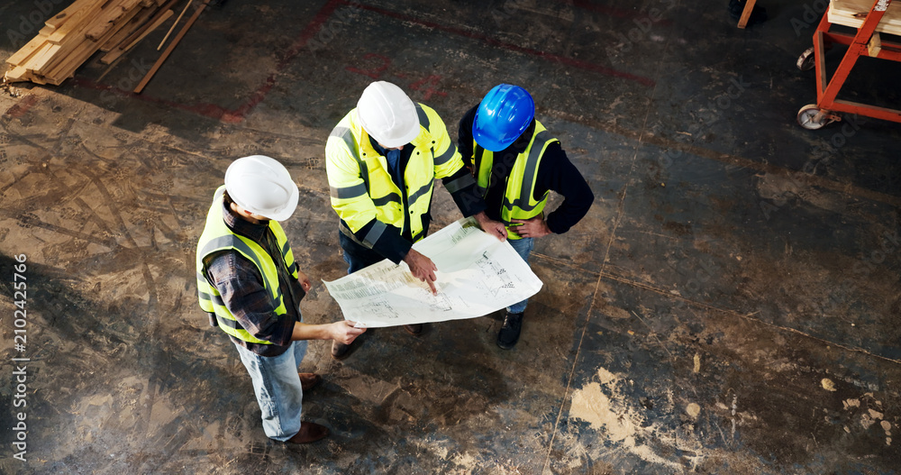 Obraz premium Top view, architect and planning with blueprint at construction site, building development or layout. Engineer team, people and discussion with document for infrastructure design, review and above