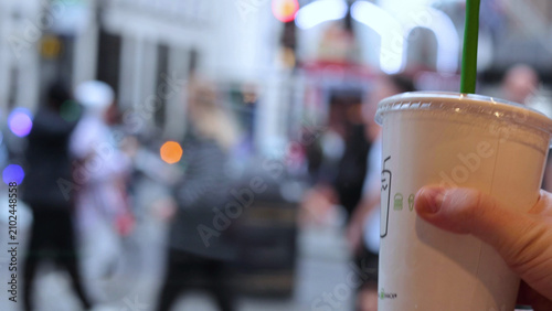 Quadro su tela Close Up of Hand Holding Beverage Cup on Busy London Street