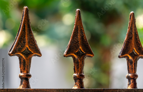 wrought iron fence. close-up macro shot of three metal fence finials lined up in a row. vintage wrought iron or cast iron fence finials, specifically designed in a spear-like or arrowhead shape.