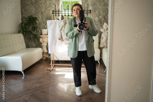 Photography Woman photographer in jacket with camera with flash in hands