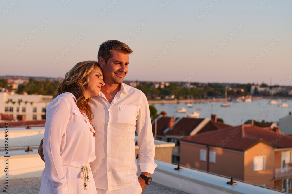 Obraz premium Romantic Couple On Rooftop Balcony At Sunset With Sea View Over Umag Harbor