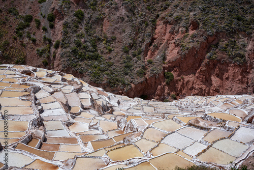 Fotografie Terraces of the Maras salt pans descend a reddish hillside in the Sacred Valley