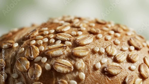 Ultra Macro Shot of Whole Grain Bun Texture Covered with Oats and Sesame Seeds on a Pale Green Background