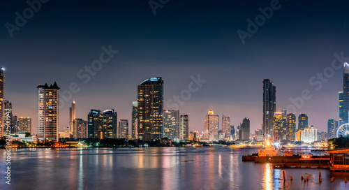 фотографія Panoramic Bangkok cityscape at night featuring illuminated skyscrapers beside Chao Phraya River