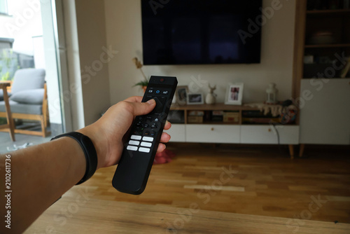 Quadro su tela A person holding a remote control to turn on a TV