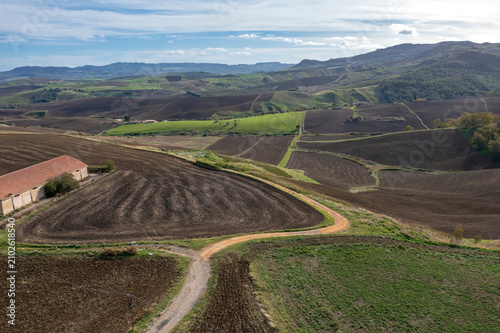 Foto Aerial view of rolling agricultural hills with plowed fields, a country road, an
