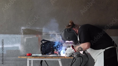 Fabricator in safety gear assembling metal part using electrode holder during welding process