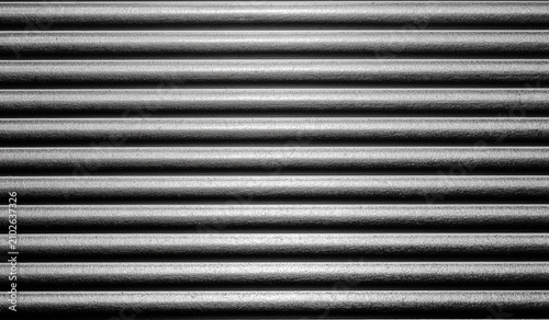 Detailed close up of dark gray corrugated metal surface with parallel horizontal lines creating rhythmic linear pattern design.