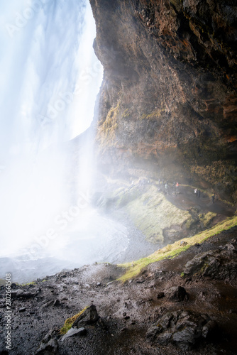 Cuadro en lienzo vertical photograph of people on a trail pass behind Seljalandsfoss, an Icelandic waterfall south of Reykjavik, on a cloudy day