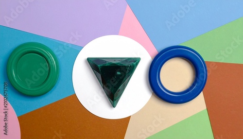 Interlocking blue and white rings with green faceted gem on pastel striped background, geometric modern design emphasizing unity, creativity, and vibrant visual harmony.