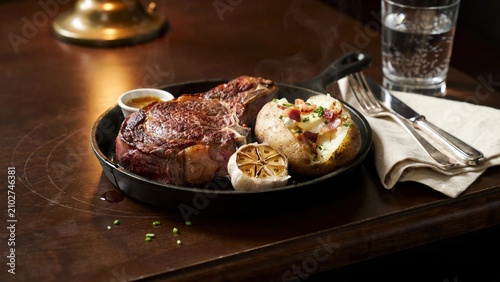 Juicy steak with baked potato and garlic served in cast iron pan full hd 4k stock image download beef
