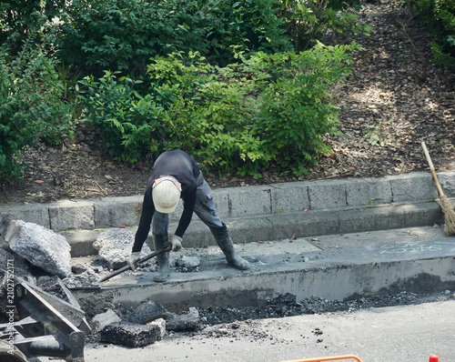 夏の昼の都市の街の道路工事現場で働く作業員の姿