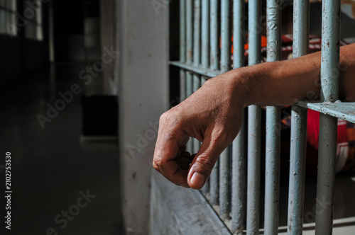 Canvastavla Desperate Hands of Inmate Behind Bars, Isolated on Black