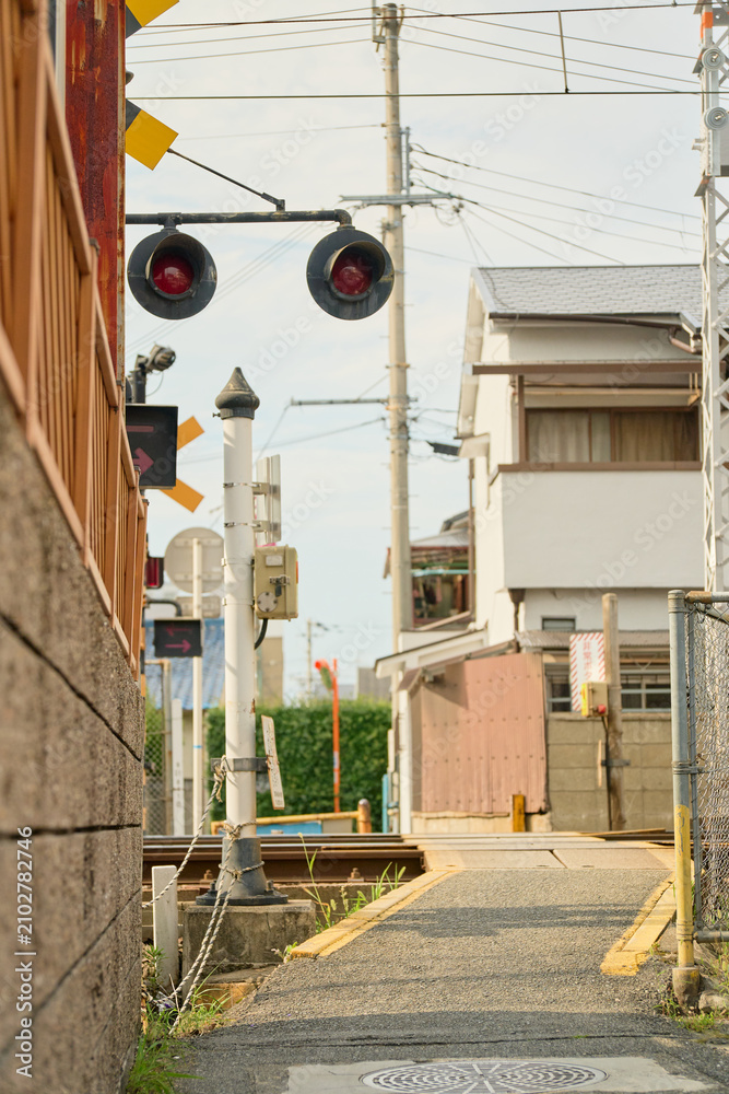 Naklejka premium コンクリート塀と民家に挟まれたローカルな線路の踏切。非常ボタンの表示