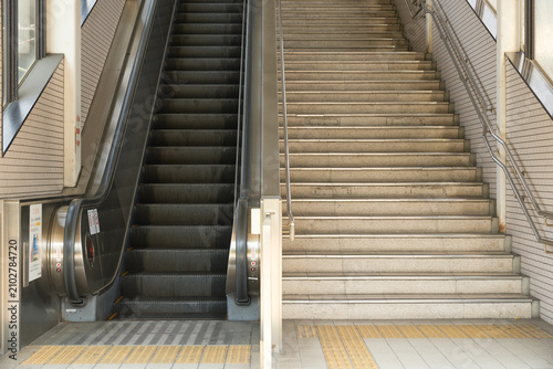 Cuadro en lienzo 点字ブロックが敷かれた駅構内のエスカレーターと階段の構図。非常停止ボタンと安全警告ステッカー