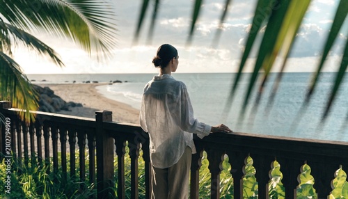Woman wearing white linen shirt standing peacefully on wooden balcony