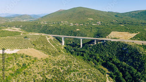Foto Modern highway bridge spanning a green mountain valley with olive groves in Herz