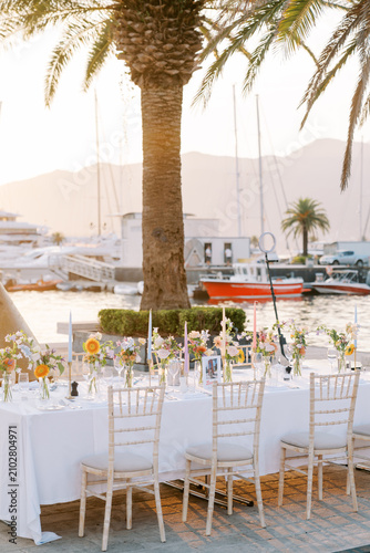 Elegant seaside feast. Serene waterfront dining scene with luxurious accents and floral arrangements