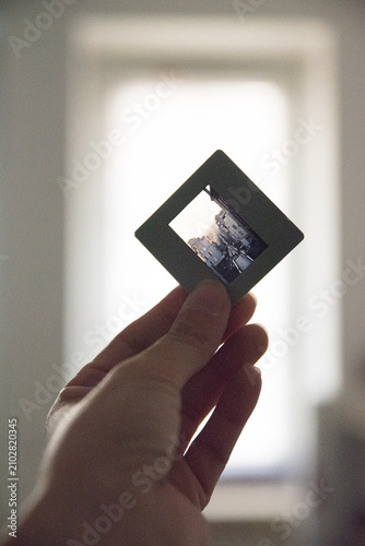 nostalgic hand holding slide near window in indoor setting close-up photography memory moment 