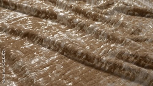 Close up view of luxury crushed velvet fabric with shimmering light reflections, showing detailed texture and folds.