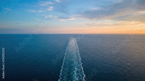 Boat wake line cutting across calm ocean at sunset