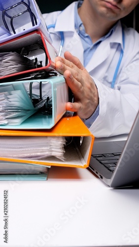 Konstfotografi Doctor's hand organizing a large stack of patient medical records and ring binders