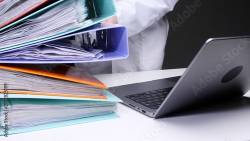Foto Professional person organizing many stacked binders full of files and important