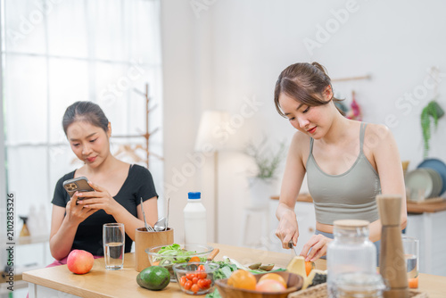 Woman kitchen cooking phone vegetable fruit meal home lifestyle young woman preparing fresh food while friend uses mobile device at bright table