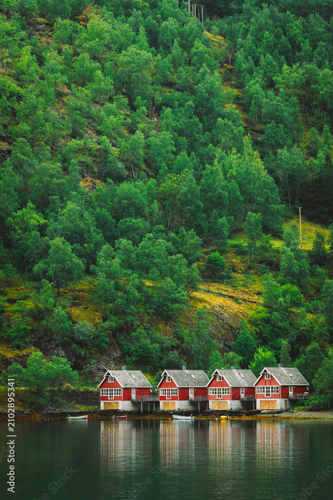 Fototapeta premium Classic red Norwegian boathouses along the edge of the fjord. Sognefjord port in Flam, Norway. Red wooden Docks in small tourist town of Flam on western side of Norway deep in fjords.