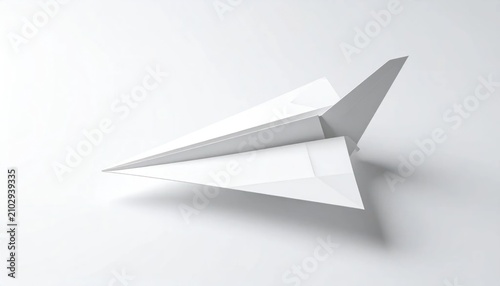 Minimalist white paper airplane against white studio backdrop.