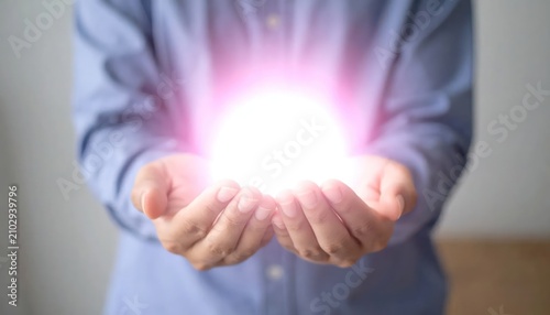 Person holding bright glowing light orb in hands.