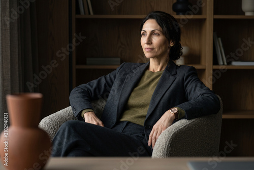 A serene leader seated in a designer armchair, exuding refined professional composure. Editorial capture of soft textures, organic decor, and the Quiet Luxury of a tailored executive space.
