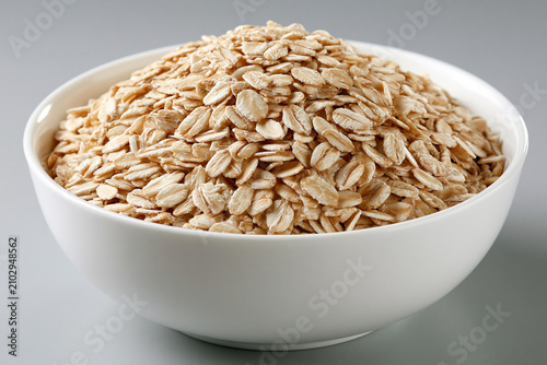 Piles of oats in a white bowl on a gray background