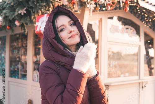 Photography Woman wearing a warm red coat and white mittens adjusting Christmas tree ornaments