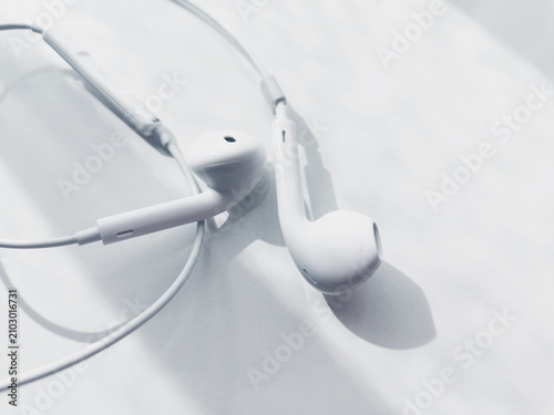 White earphones resting on bright reflective table surface