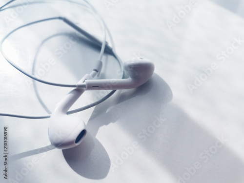 White earphones coiled on bright reflective tabletop surface