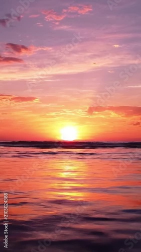 Stunning Sunset Over Calm Ocean Waters, with Vibrant Hues of Pink, Orange, and Purple Reflected on the Surface, Creating a Serene Evening Atmosphere