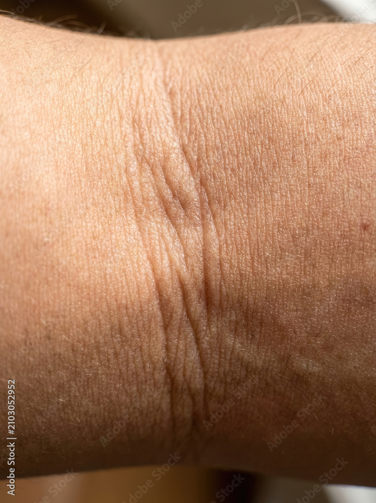 Fototapeta premium Skin texture close up showing fine lines and creases on elbow area, highlighting natural aging