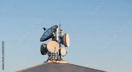 Telecommunications Satellite Dish Array Mounted on Rooftop Against a Clear Blue Sky