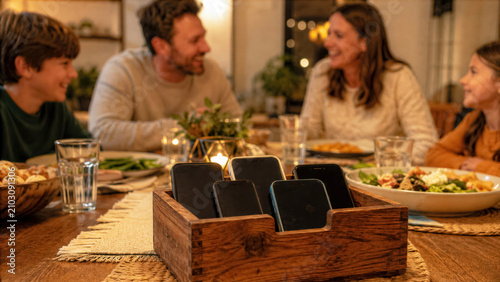 Family dinner with smartphones placed in a no phones basket in the center for social connection and detox