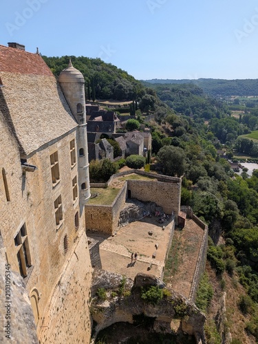 High-angle view of Château de Beynac with its stone watchtower turret looking down on the lower fortifications and the medieval village below in Dordogne, France