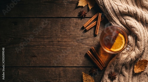 Flat lay of warm tea with cinnamon and cozy knit sweater on wooden table